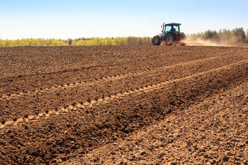 Fototapeta premium cultivator operates on ploughed field makes dust