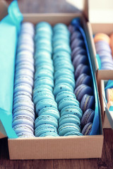 Naklejka premium Varicolored tasty macaroons in cardboard box on wooden table
