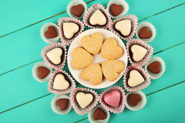 Valentine's Day concept. Composition of delicious chocolate candies and tasty cookies on turquoise wooden background