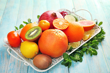 Juicy composition of tropical fruits on a tray on wooden background