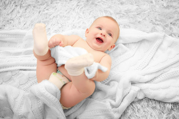 Adorable baby in diaper with blanket on the floor, close up