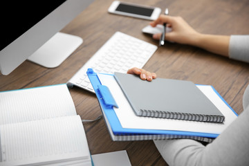 Work concept. Clipboard and notebook in woman hands. Computer and smart phone on wooden table