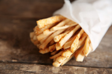 Bread sticks grissini with sesame seeds in craft pack on a wooden background