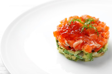 Delicious salmon tartare with red caviar on white plate