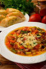 Minestrone- italian soup with vegetables on brown wooden table.