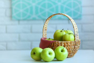Ripe green apples in basket on a kitchen table