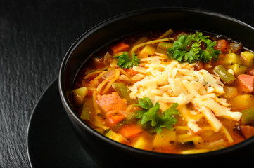 Minestrone -italian soup with vegetables. Black bowl on black board.