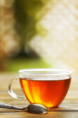 Glass cup of tea on wooden table against blurred background