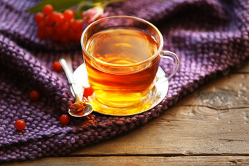 Glass cup of tea, purple blanket and berries on wooden background