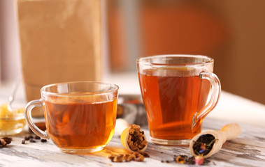 Glass cup of tea with spices on blurred background