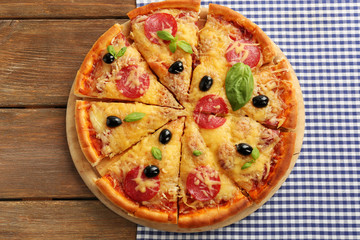 Fresh baked pizza on a wooden table, top view
