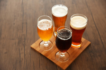 Glasses with different sorts of craft beer on wooden tray