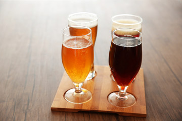 Glasses with different sorts of craft beer on wooden tray