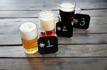 Glass mugs with different sorts of craft beer and numbering on wooden table