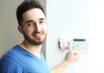 Man entering code on security system keypad indoors