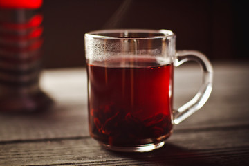 A Cup of hibiscus tea from Sudanese rose with lemon and cinnamon sticks. Brew in teapot on a black wooden background