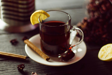 A Cup of hibiscus tea from Sudanese rose with lemon and cinnamon sticks. Brew in teapot on a black wooden background