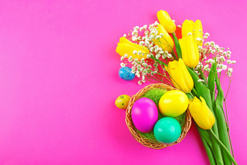 Multicoloured Easter eggs and tulips on pink background