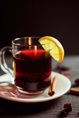 A Cup of hibiscus tea from Sudanese rose with lemon and cinnamon sticks on a black wooden background