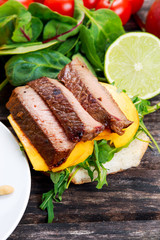 Bun with grilled roast beef, mango and arugula.