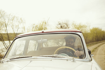 Fototapeta na wymiar Man with beard driving a retro car