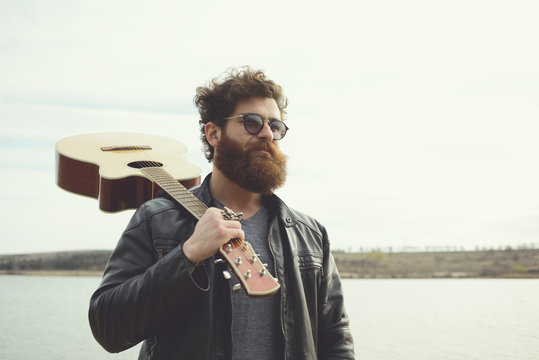 Bearded man and guitar, near river