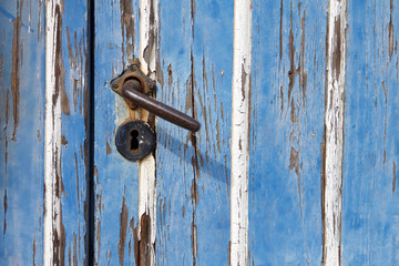 Nahaufnahme von verwitterndem blauen Holztor mit Türklinke