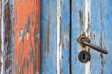 Nahaufnahme von verwitterndem blauen Holztor mit Türklinke