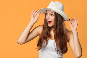 Fototapeta premium Surprised happy woman looking sideways in excitement. Isolated on orange background