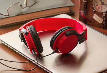 Laptop, red headphones, book  and  clock at office desk. Shallow depth of field. 