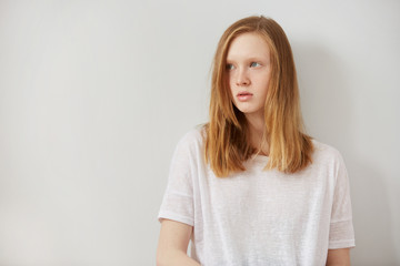 Fototapeta premium Woman wearing white blank t-shirt standing on the background of a wall