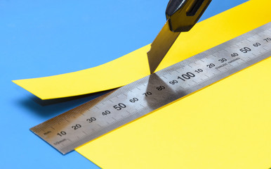  yellow paper with a knife and a stainless steel ruler