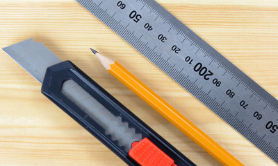 Cutter , wood pencil and ruler on wooden table