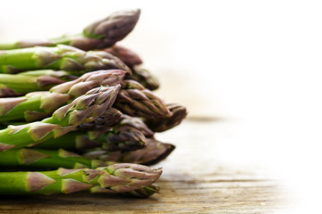 green asparagus on a bright rustic wooden board, background fades to white