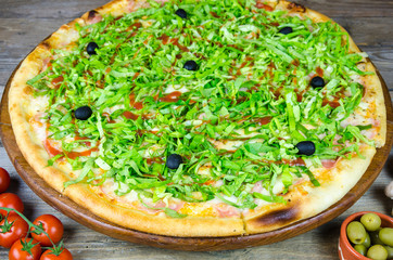 Large pizza decorated with lettuce and olives