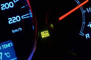 Close up of car dashboard with green hybrid mode icon on.