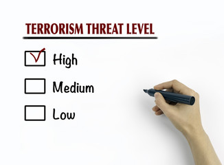 Woman's hand writing terrorism threat level on white background