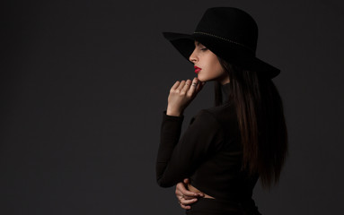Fashion portrait of young beautiful woman model in casual wear. Black boots, hat and black dress. Copy space. 