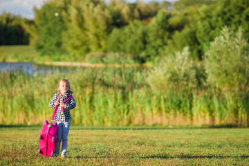 Little girl walking with luggage ready for traveling outdoors