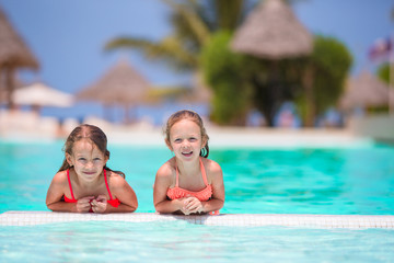 Fototapeta na wymiar Adorable little girls playing in outdoor swimming pool
