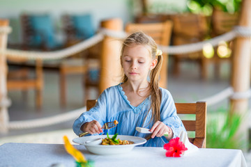 Adorable little girl having lunch at outdoor cafe