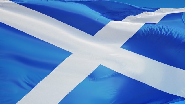 Scotland flag waving in slow motion against clean blue sky, seamlessly looped, close up, isolated on alpha channel with black and white luminance matte, perfect for film, news, digital composition