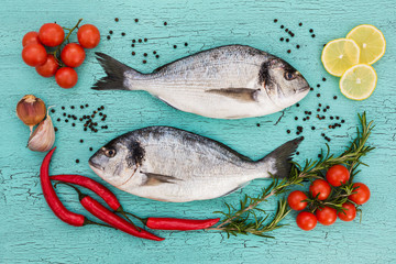 Raw dorado fish, cherry tomatoes, garlic and lemon on blue background. Top view
