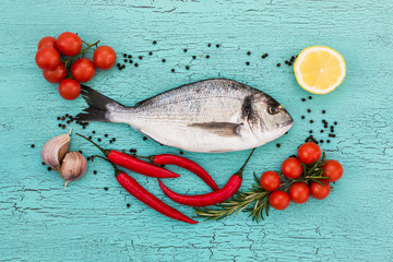 Raw dorado fish, cherry tomatoes, garlic and lemon on blue background. Top view