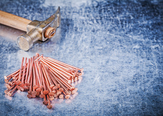 Vintage claw hammer heap of brass construction nails on metallic