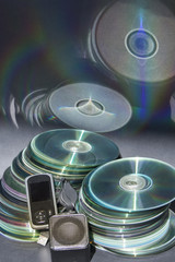 CD y  DVD formando dos columnas con reflejos,  junto a reproductor MP3 con altavoz