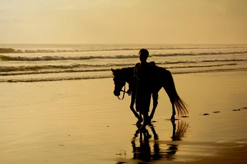 Foto op Canvas Silhouette of man walking a horse at the beach at sunset, Seminyak Beach, Bali, Indonesia © ottosphotos