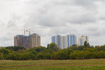 Fototapeta na wymiar City park and high-rise buildings under construction. Urban