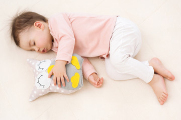 Sleeping and dreaming beautiful baby girl toddler with an owl toy on the bed