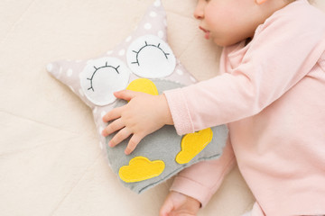 Close-up portrait of adorable baby toddler girl with an owl toy